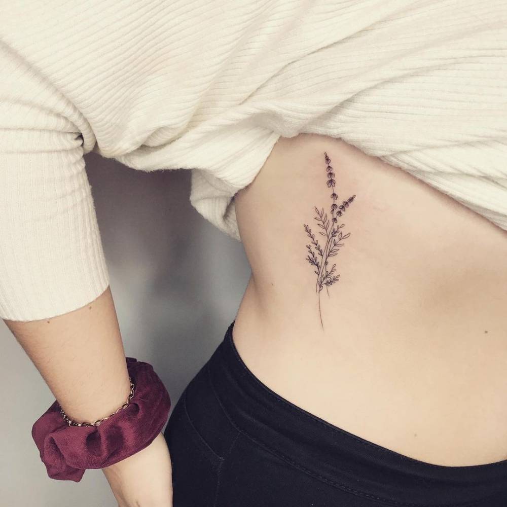 Fine line lavender tattoo on the rib.
